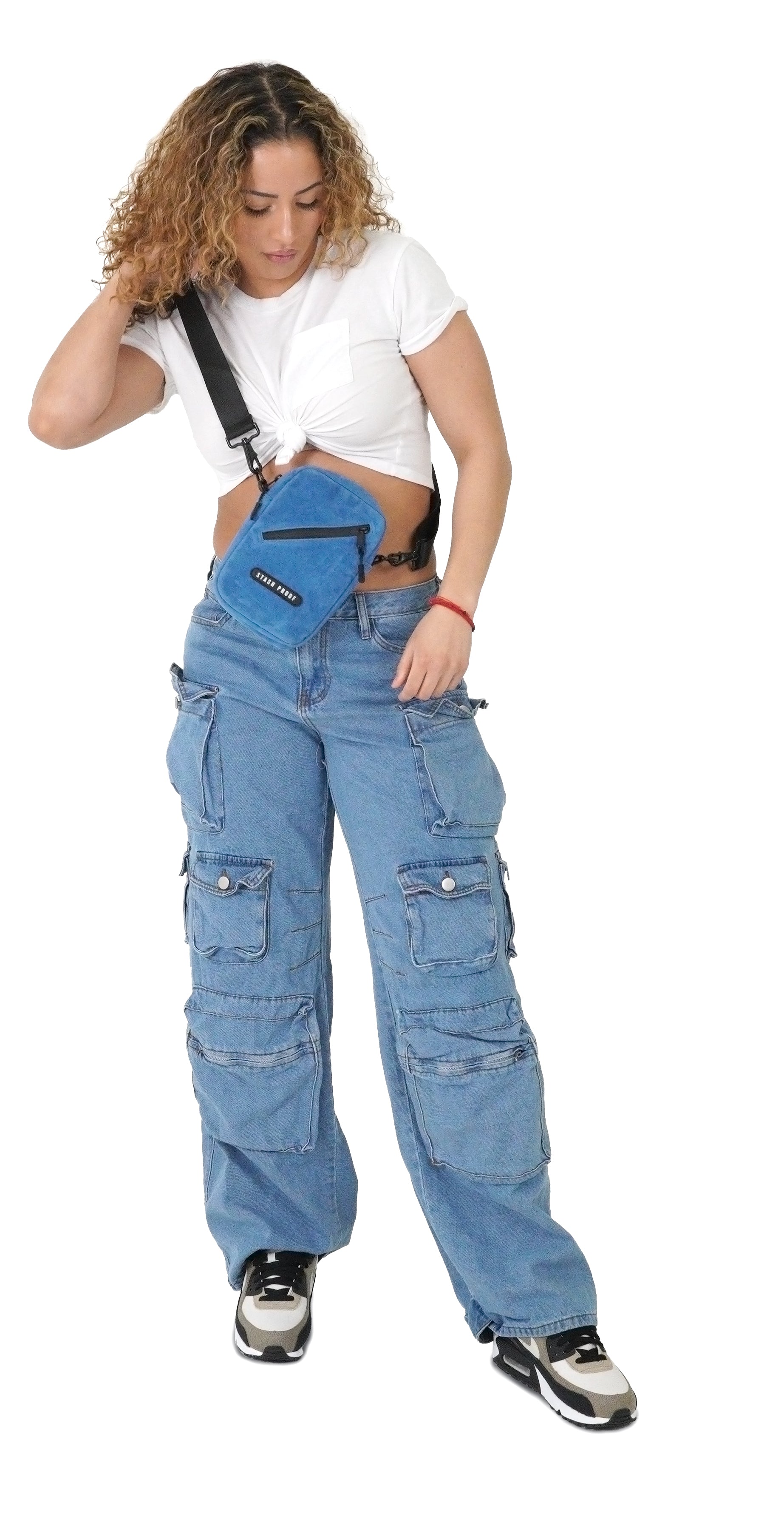 Model with white shirt and blue jeans holding blue suede stash bag as crossbody bag