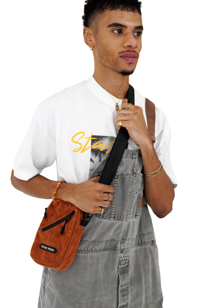 Model holding brown suede Stash bag as crossbody bag, model on white background