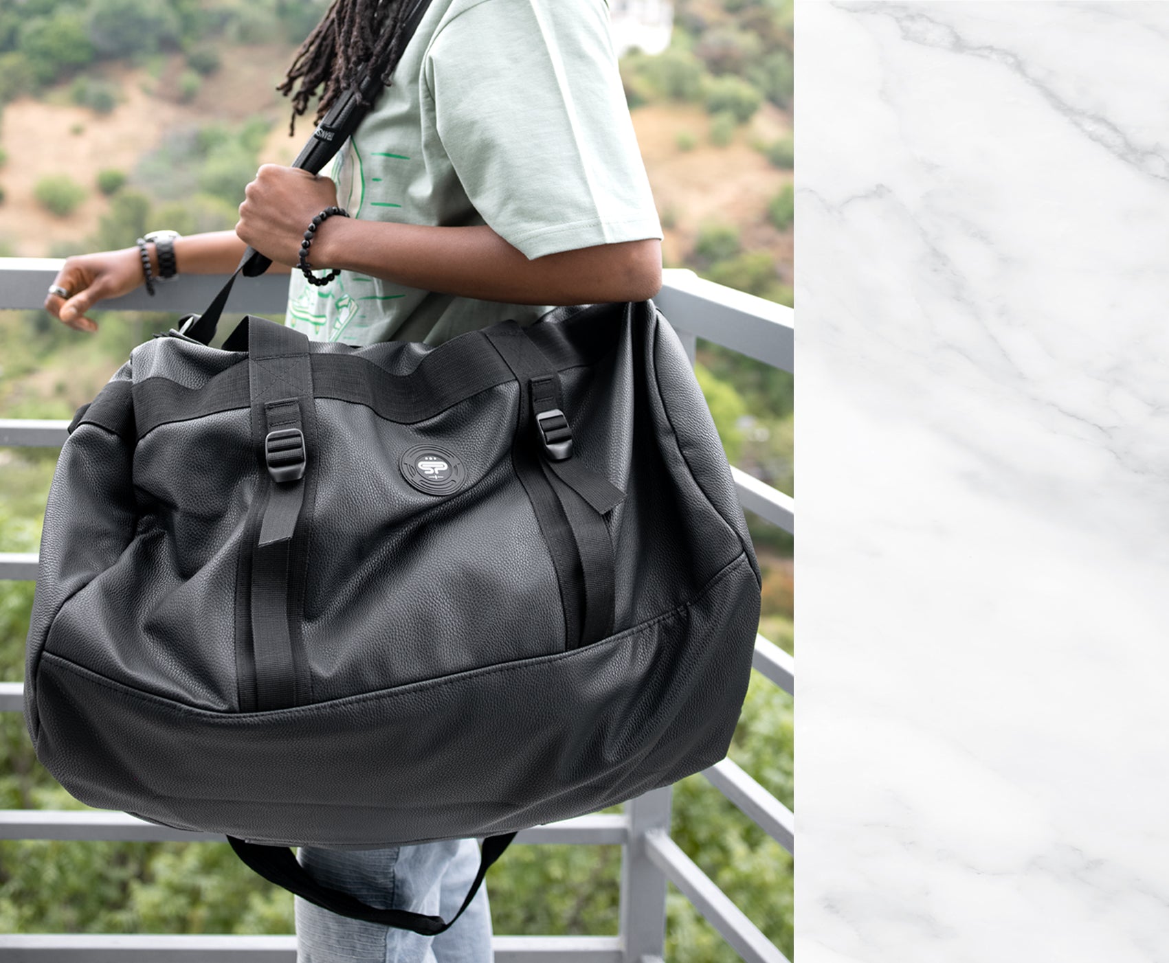 Woman standing near railing holding black large duffel bag by Stash proof