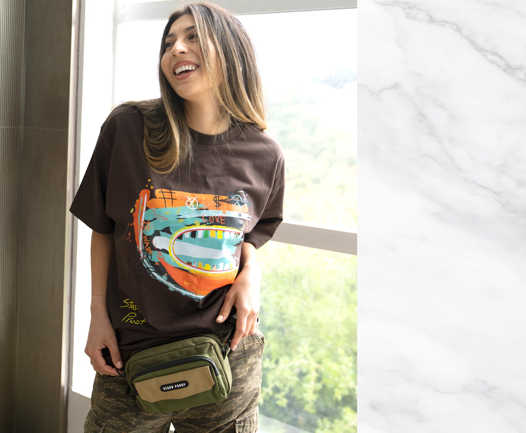 Woman standing next to window wearing Green and Tan Flip bag by Stash Proof